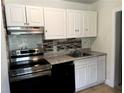 Compact kitchen featuring white cabinets, black appliances, and tiled backsplash at 210 Ormond Sw St, Atlanta, GA 30315