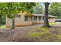 A single-story brick home features black shutters, complemented by the shade of mature trees in the front yard at 574 Horseshoe Sw Cir, Lilburn, GA 30047