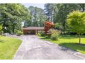Quaint brick home featuring mature shade trees, covered carport, and long driveway at 5400 Francis Ave, Stone Mountain, GA 30087