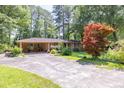 Quaint brick home featuring mature shade trees, covered carport, and long driveway at 5400 Francis Ave, Stone Mountain, GA 30087