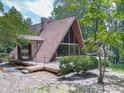 Exterior of A-frame home featuring a wooden deck and large windows, surrounded by lush greenery at 1467 Shiloh Trail East Nw, Kennesaw, GA 30144