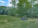 View of a golf course with a golf cart parked on the green, surrounded by mature trees at 1467 Shiloh Trail East Nw, Kennesaw, GA 30144