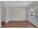 An open dining room with hardwood floors, detailed molding, and a modern pendant light fixture at 5891 Buckner Creek Dr, Mableton, GA 30126