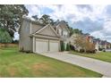 Well-manicured lawn of this two-story home and long concrete driveway leading to the attached garage at 5891 Buckner Creek Dr, Mableton, GA 30126