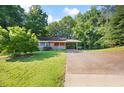 Quaint brick home with a covered front porch and attached carport, nestled among mature trees and a green lawn at 2005 Dallas Sw Hwy, Marietta, GA 30064