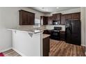 This kitchen features dark wood cabinets, granite countertops, bar and black appliances at 98 Concord Pl, Hiram, GA 30141