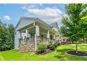 A beautiful, modern home with a stone foundation, large front porch, and lush, green landscaping at 9117 Hanover St, Lithia Springs, GA 30122