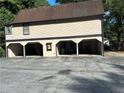 Exterior shot showcasing a three-car garage with individual bays on a property with mature trees at 1455 Stone Mill Trce, Stone Mountain, GA 30083