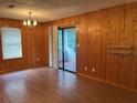 View of a living room with wood-paneled walls, laminate flooring, and a sliding glass door to the outside at 1455 Stone Mill Trce, Stone Mountain, GA 30083