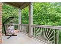 Relaxing covered porch features an egg chair swing and decorative railing, providing a serene outdoor retreat at 7535 Antique Barn Ave, Cumming, GA 30041