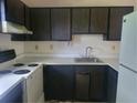 View of the kitchen including dated appliances, dark cabinets, laminate countertops and a stainless steel sink at 1867 Myrtle Sw Dr # 3, Atlanta, GA 30311