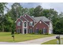 Attractive brick home featuring a well-kept lawn, driveway, and lush, mature landscaping at 6625 Eagle Pt, Suwanee, GA 30024