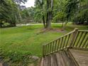 View of the expansive front yard featuring a mix of lush greenery, mature trees, and a gently sloping landscape at 512 S Holly Springs Rd, Woodstock, GA 30188