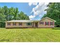 Inviting ranch-style home featuring a large lawn, complemented by charming red window shutters at 35 Brookside Ct, Villa Rica, GA 30180