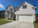 Two-story white brick home featuring an attached two-car garage and well-maintained landscaping at 3332 Grace Farm Ln, Buford, GA 30519