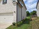 Home exterior featuring a side view of the garage and a view of the well maintained lawn at 3332 Grace Farm Ln, Buford, GA 30519