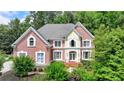 Beautiful two-story brick home with lush landscaping and a classic architectural design, nestled among mature trees at 12130 Helleri Holw, Alpharetta, GA 30005