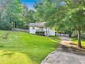 Quaint home with a sloping lawn, mature trees, and a driveway leading to a cozy front porch at 394 Thornbrooke Dr, Hiram, GA 30141