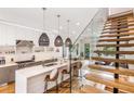 Bright, modern kitchen with a white island, pendant lighting, stainless steel appliances, and open staircase with glass railing at 167 Sampson Ne St, Atlanta, GA 30312
