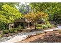 Inviting home exterior with mature trees, stone accents, and a winding driveway at 4850 Lake Fjord Pass, Marietta, GA 30068