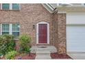 Close-up of a front door with brick surround and manicured landscaping at 1727 Shire Village Dr, Sugar Hill, GA 30518