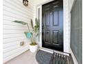 Inviting entryway featuring a dark front door, white siding, a decorative plant, and a charming welcome mat at 2647 Midler Ct, Buford, GA 30519