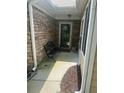 Covered front porch with a wrought iron bench, stone facade, and the house number above the door at 2191 Rockbridge Road # 2603, Stone Mountain, GA 30087