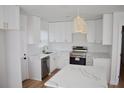 Modern kitchen with white cabinets, quartz countertops, stainless steel appliances, and stylish light fixtures at 2502 Tupelo Se St, Atlanta, GA 30317