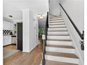 Bright hallway featuring hardwood floors, a staircase with a black banister, and a view into the kitchen at 5037 Laurel Springs Se Way, Smyrna, GA 30082