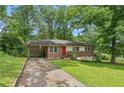 Traditional brick home with attached carport surrounded by mature trees and green lawn at 4653 Ridgewood Dr, Forest Park, GA 30297