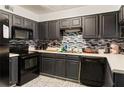 Galley kitchen with black cabinets, modern appliances, mosaic backsplash, and white countertops at 1523 Dillard Rd, Stone Mountain, GA 30088
