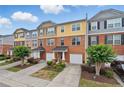 Street view of charming townhomes featuring brick, colorful siding, front garages, and well-maintained landscaping at 771 Tulip Poplar Way, Lawrenceville, GA 30044