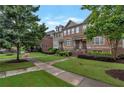 Beautiful brick townhomes with manicured lawns, mature trees, and inviting sidewalks under a blue sky at 7850 Willoughby Ct, Alpharetta, GA 30005