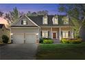 Charming two-story home featuring dormer windows, a covered porch, and well-maintained landscaping at twilight at 150 Northshore Xing, Dallas, GA 30157