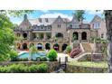 Luxury home showcasing a stunning stone facade, arched terraces, a pool, and meticulously landscaped backyard at 4745 Cuyahoga Cv, Suwanee, GA 30024