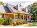 Close up of the charming brick house and its inviting front porch with an American flag at 184 Wildflower Dr, Social Circle, GA 30025