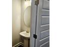 Cozy powder room with a pedestal sink, round mirror, and a stylish paneled door at 145 Scarlett Place Dr, Bowdon, GA 30108