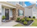Close-up of front entrance showcasing stone facade, black shutters, and meticulously manicured landscaping with lush greenery at 36 Ivy Chase Loop, Dallas, GA 30157
