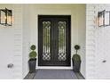 Elegant front door with glass panels, flanked by stylish sconces and manicured topiaries at 2243 Cain Cir, Dacula, GA 30019