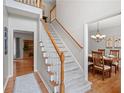 Traditional staircase featuring carpeted steps, wooden handrail, and views into dining and living spaces at 2081 Township Dr, Woodstock, GA 30189