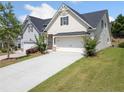 Side view of cozy home showing tidy lawns, attractive plantings, and long driveway to the two-car garage at 4571 Grenadine Cir, Acworth, GA 30101
