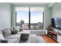 Bright living room featuring a gray couch, ottoman, large windows, and beautiful city views at 3445 Stratford Rd # 3102, Atlanta, GA 30326
