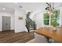 Bright dining area featuring a wooden table, elegant light fixture, staircase, and large windows at 24 Becker Nw Pl, Atlanta, GA 30307