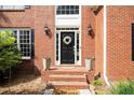 Charming brick home featuring a black front door adorned with a wreath, flanked by sconces and potted plants at 6435 Ivey Creek Cir, Cumming, GA 30040