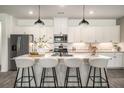 Bright kitchen featuring a large center island with seating, stainless steel appliances, and modern pendant lighting at 947 Edwin Ln, Sugar Hill, GA 30518