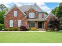 Beautiful two-story red brick home with a lush green lawn and symmetrical landscaping at 2260 Falkirk Pointe Dr, Marietta, GA 30062