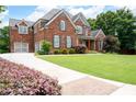 Spacious home featuring a brick exterior, large driveway, and meticulously maintained front lawn and landscaping at 2260 Falkirk Pointe Dr, Marietta, GA 30062