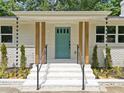 Close up of front entrance boasting natural wood pillars, teal door, and contemporary black metal railings at 401 Cottonwood Dr, Woodstock, GA 30189