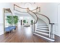 Grand foyer with curved staircase, chandelier, high ceilings, hardwood floors, and decorative mirror at 70 Finch Forest Trl, Atlanta, GA 30327