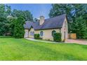 Cozy home featuring mature trees, a tidy lawn, a circular walkway, and a side yard gate at 10 Briarcliff Pl, Stockbridge, GA 30281